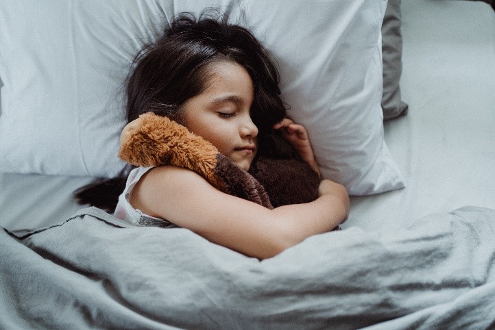 Enfant dans son lit qui fait un câlin à son nounours - Blog Enurésie Love & Green