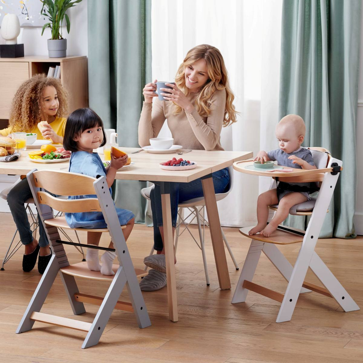 Famille heureuse mangeant autour d'une table en bois dont deux enfants sont assis sur des chaises Enock