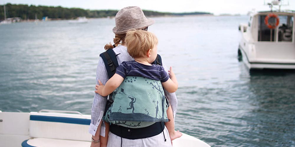 Bettina portant son fils en Buzzidil Preschooler sur un bateau face à la mer